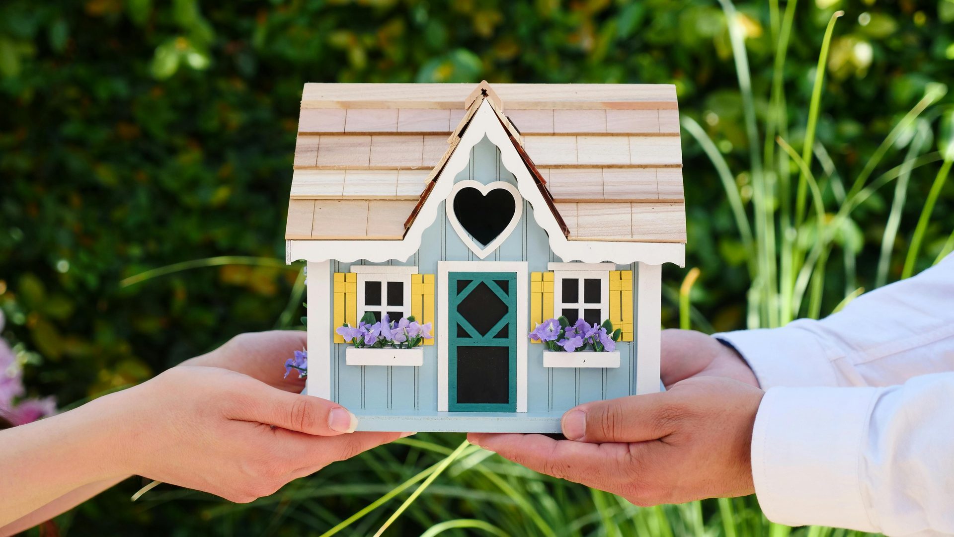 Hands holding a miniature house model with heart window - Florida mortgage lender